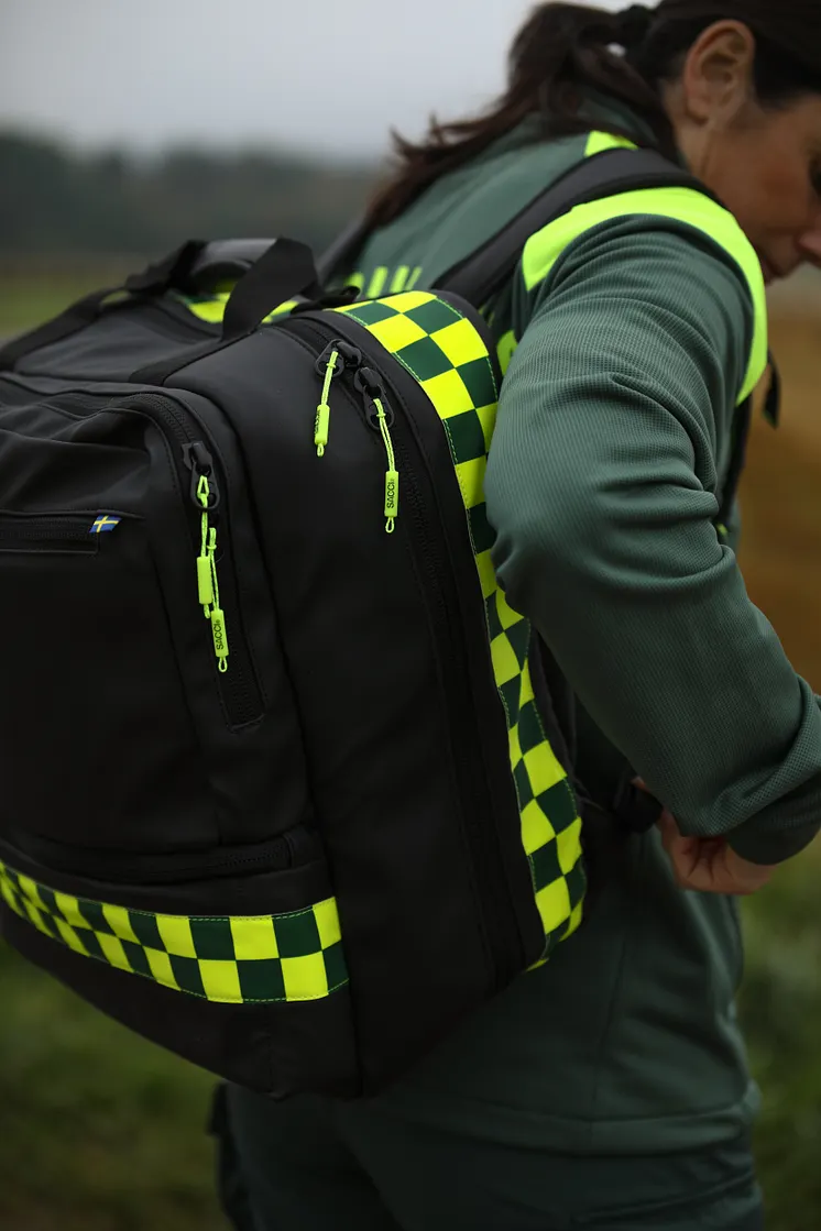 Ambulanssjukvårdare med svart sjukvårdsryggsäck med reflexer