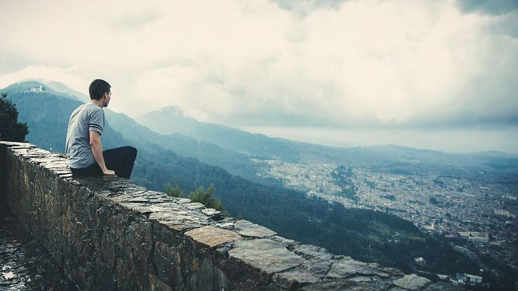 Man sitting on rock wall and overlooking city