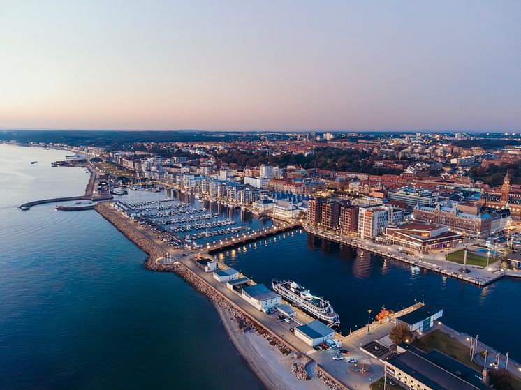 Drönarbild över norra hamnen i Helsingborg. Det är lätt kvällsljus. Man ser båtarna i hamnen i förgrunden och längre bak stad