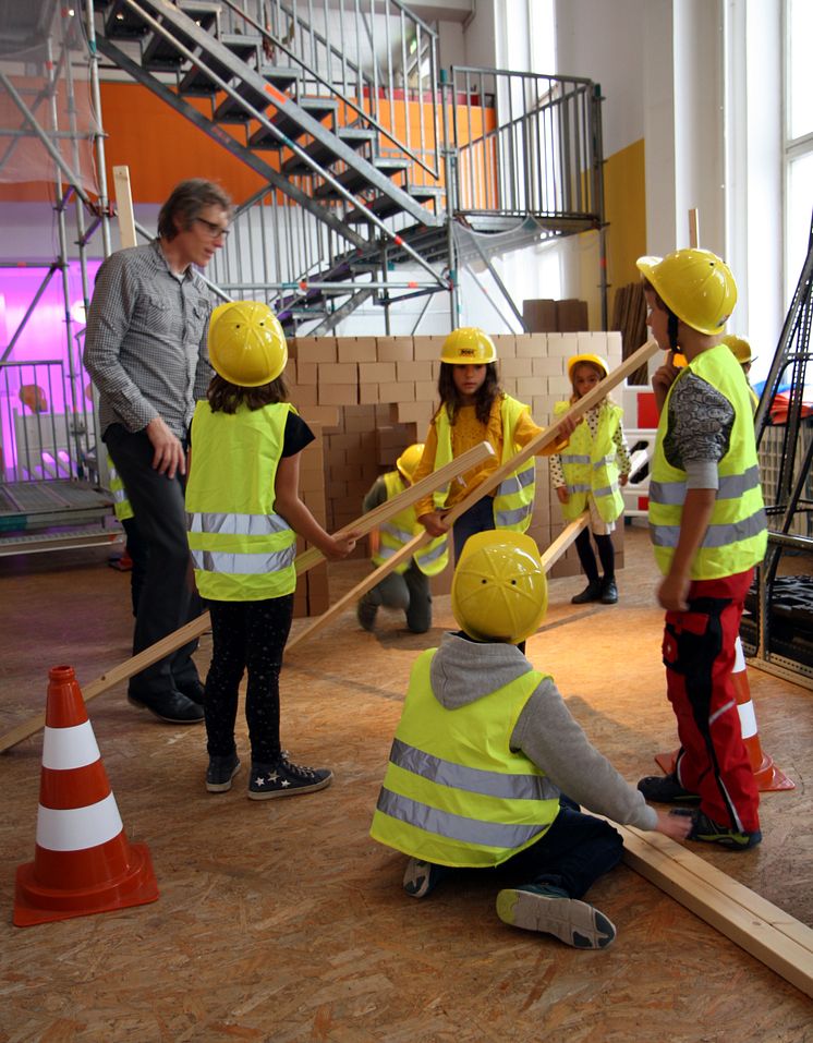 Kinder errichten zusammen einen Dachstuhl aus Holz