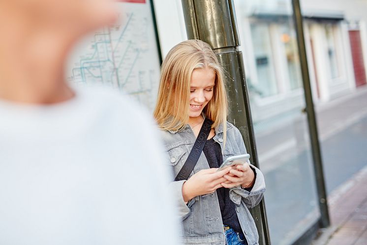 JLT_Flicka på hållplats med mobil