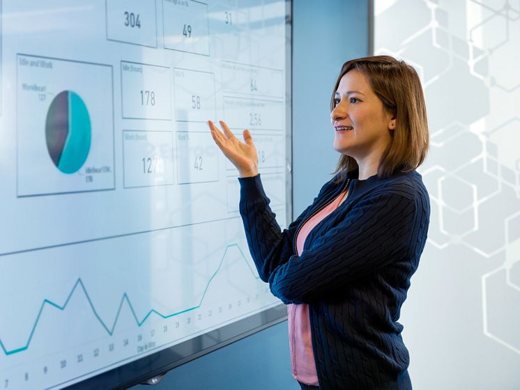 Woman standing next to screen looking at graphs and numbers.jpeg