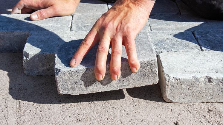 Hand som lägger marksten på stenmjöl.