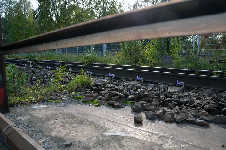 Konventionell järnväg möter järnvägsräls på solig betongplatta