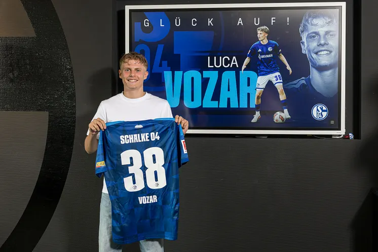 Luca Vozar zeigt sein Schalke-Trikot mit der Rückennummer 38.