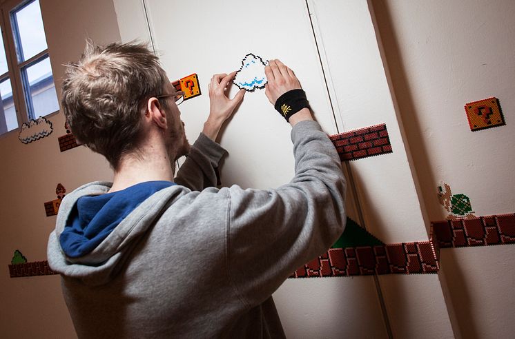 Ateljé dataspel, Martin Hagegård monterar sitt verk på väggen. Foto: Anna Gerdén