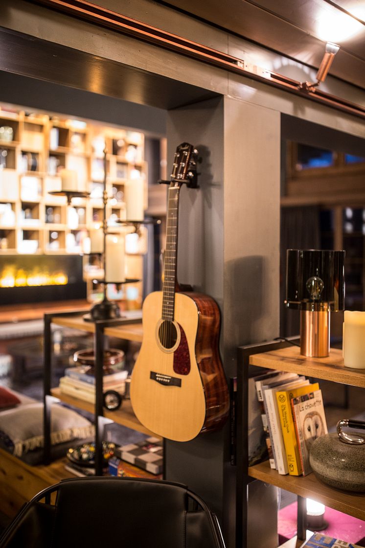 Gitarr och böcker i vardagsrummet på HUUS Hotel, Gstaad, designat av Stylt Trampoli