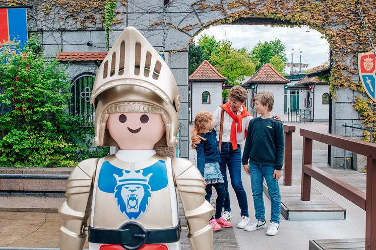 Eine Großmutter mit ihrer Enkelin und ihrem Enkel vor dem Eingang des Playmobil-FunParks