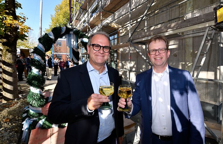 Dr. Bernd Hochberger (re.), Vorstandsmitglied der Stadtsparkasse München, stoßt zusammen mit dem Leiter des Immobilienmanagements, Michael Rubenbauer, auf das Richtfest des Neubaus in der Belgradstraße 162 an.