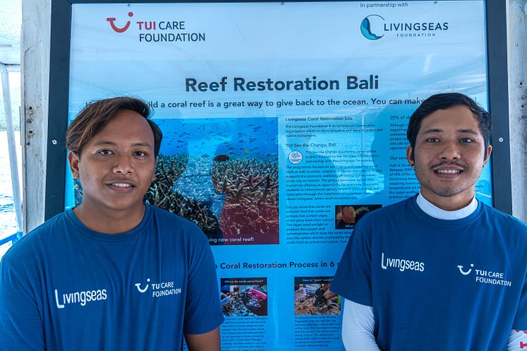 aksi henkilöä seisoo "Reef Restoration Bali" -julisteen edessä, yllään siniset TUI Care Foundation ja Livingseas -logopaidat.