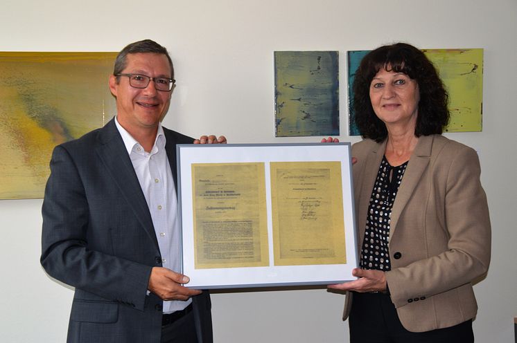 Kommunalbetreuer Frank Schneider übergab eine gerahmte Kopie des ursprünglichen Vertrags an Bürgermeisterin Helga Schmidt-Neder.
