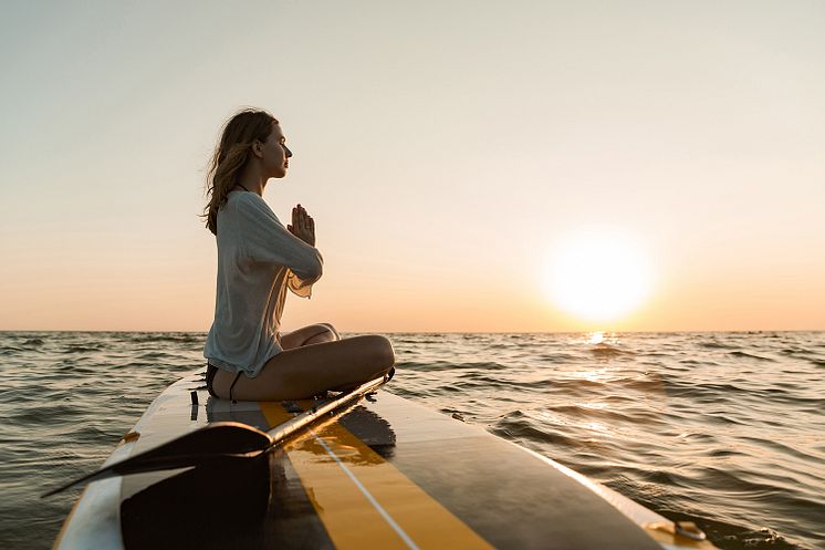 Junge Frau entschleunigt auf Paddleboard