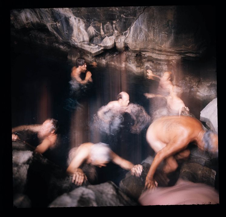 Suddig bild av män som badar i en grotta. 