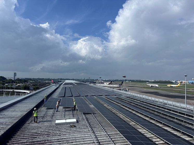 Workers installing solar panels on Terminal 3 rooftop
