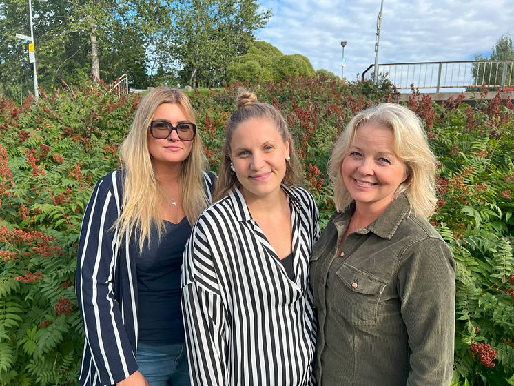 Jennifer, Matilda och Camilla framför gröna buskar. Del av bro i bakgrunden.