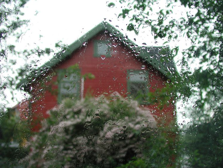 regn på vindu mot rødt hus