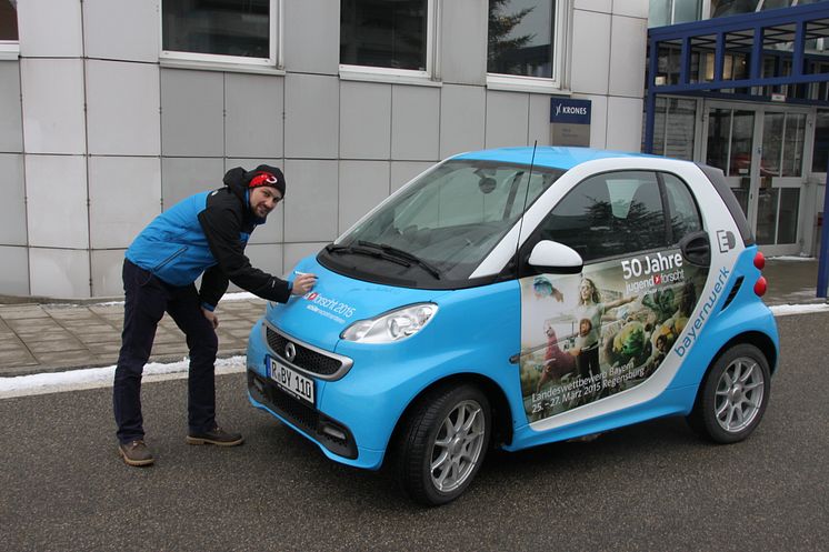 Foto: Mit dem „50 Jahre Jugend forscht E-Smart“ trifft das Patenunternehmen Bayernwerk ehemalige bayerische Preisträger, hier Lukas Kerner, und lässt diese das Elektroauto signieren.