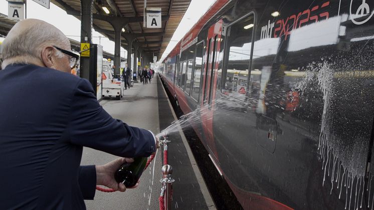 Ingvar Oldberg döper MTR Express tåg Ingvar med champagne.