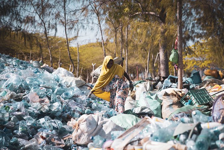 Flipflopi centre in Lamu Kenya_A woman walks through plastics collected from the community.jpg