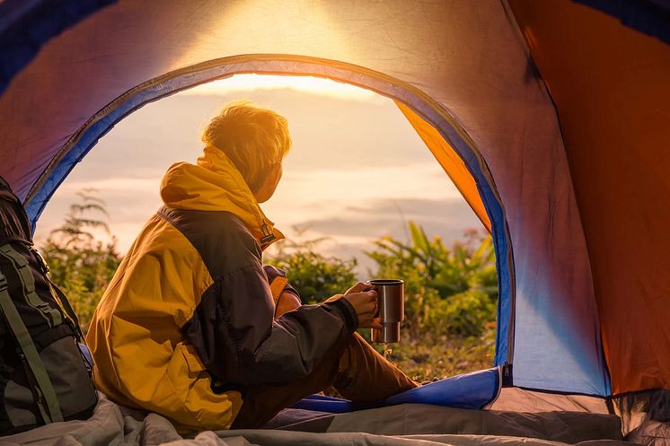young-man-sitting-tent-with-holding-coffee-cup_1150-9153