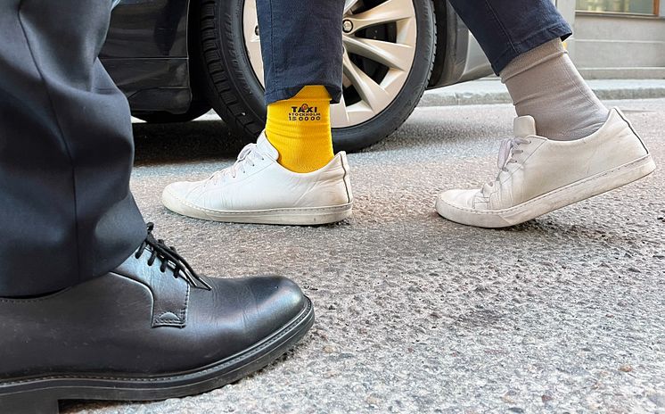 En passagerare som bär Taxi Stockholms strumpor inför "Rocka sockorna"-dagen