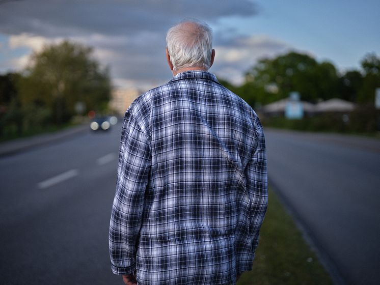 Ryggtavla av äldre man i rutig pyjamas