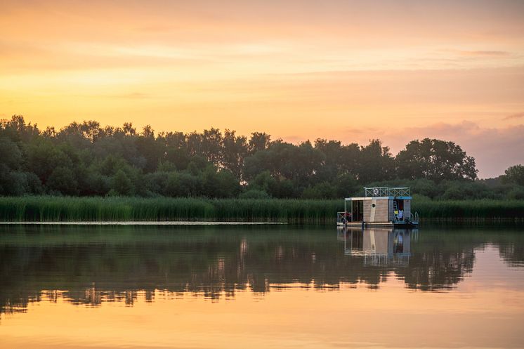 Ein_Hausbootes_im_See_bei_Sonnenuntergang_in_Brandenburg