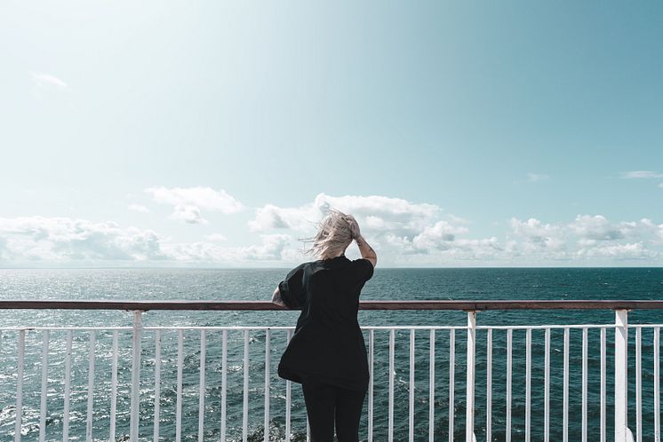 Young woman on deck looking over the sea