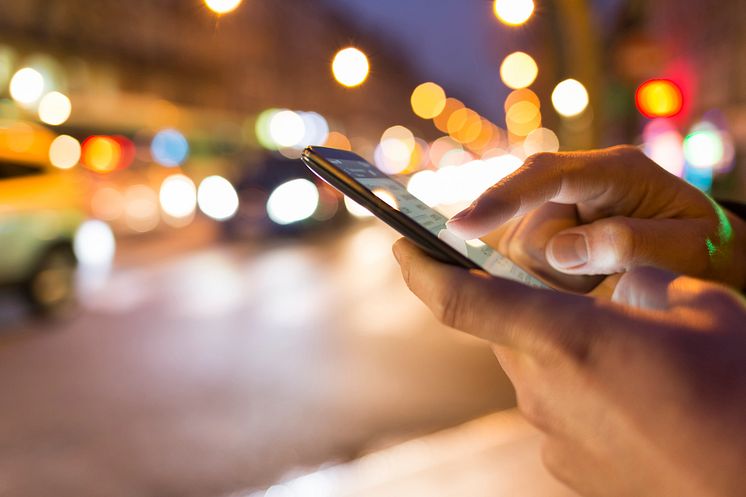 a man typing a number on his phone at night