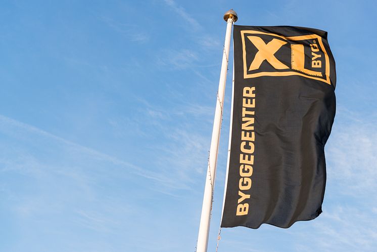 XL-BYG kædens flag mod blå himmel