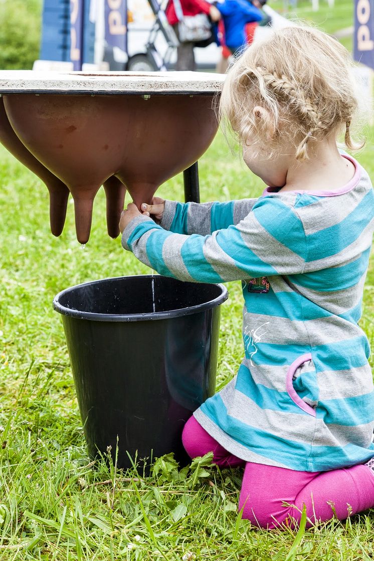 Flicka provar på att mjölka under Skånes Matfestival. 