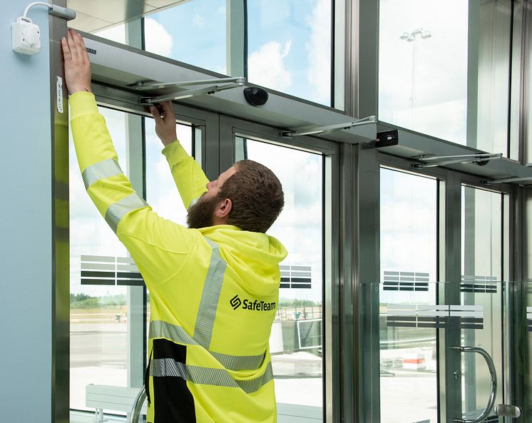 Tekniker från SafeTeam installerar dörrautomatik på dubbeldörr.