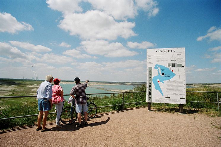 Besucher blicken auf den Störmthaler See - im Hintergrund das Kraftwerk Lippendorf 