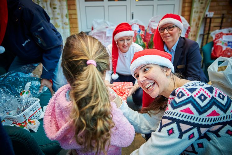 En av Mimers anställda ger en julklapp till en flicka på asylboendet