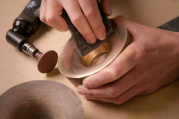 A tea light candle holder is carefully polished