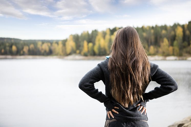 19968925-rear-view-of-woman-with-hands-on-hips-standing-by-lake