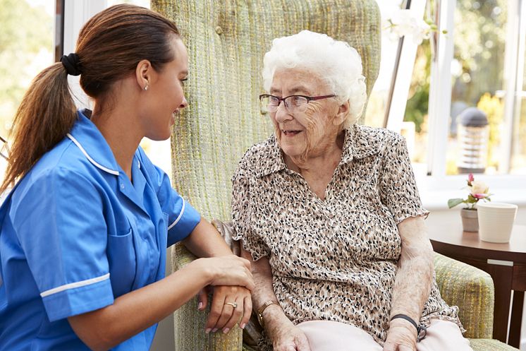 29401274-senior-woman-sitting-in-chair-and-talking-with-nurse-in.jpg