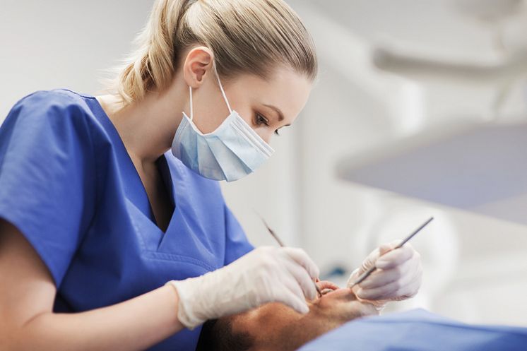 16897875-female-dentist-checking-up-male-patient-teeth