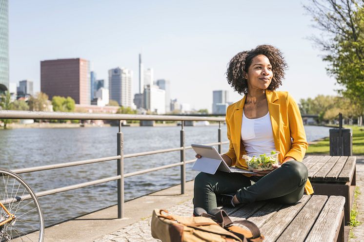 Frankfurt am Main_Frankfurt_am_Main_Junge_Frau_sitzt_mit_Laptop_und_Salat_am_Flussufer_Main,_Workation.jpg