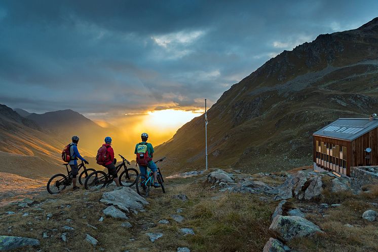 Mountainbiker genießen den Sonnenuntergang vor der Kesch Huette