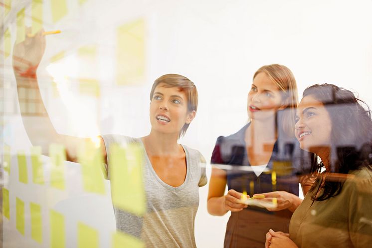 Woman drawing in the board to her coworkers