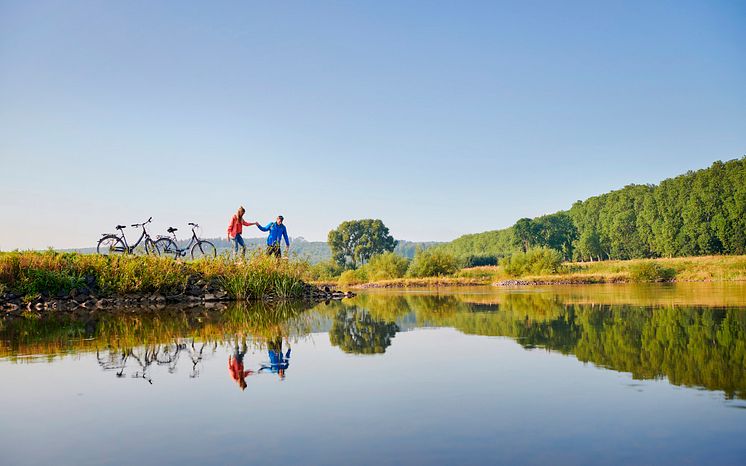 Weser-Radweg_Paar mit Fahrrädern macht Pause an der Weser (c) DZT, Jens Wegener.jpg
