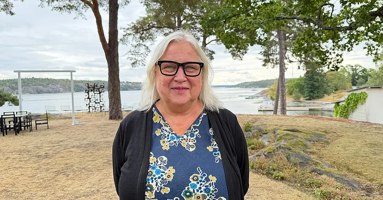Forskare Maria Åkesson har ljust hår, glasögon med mörka bågar, en blå blommig blus och en mörkblå kofta.