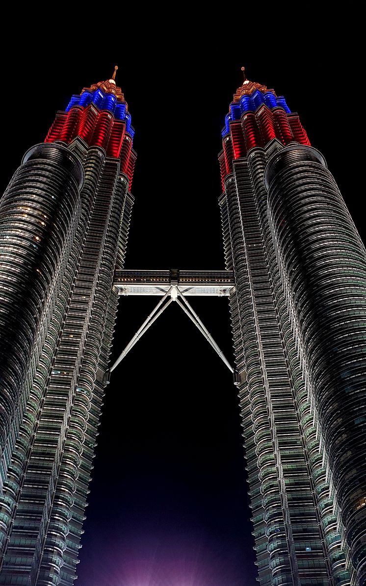 Ptronas Towers mustalla taustalla. Tornien ylinten kerrosten värit ovat punainen, sininen ja oranssi.  Keskellä skydeck.