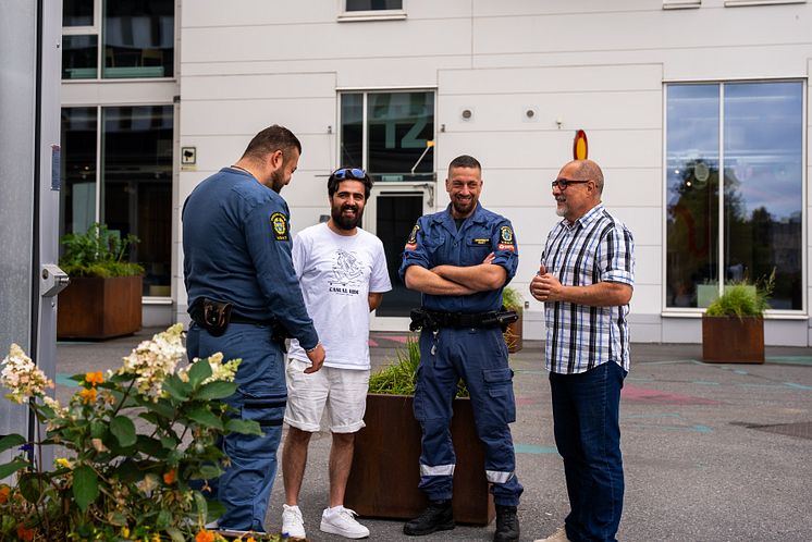 Två ordningsvakter i uniform pratar med två män i Fittja.jpg