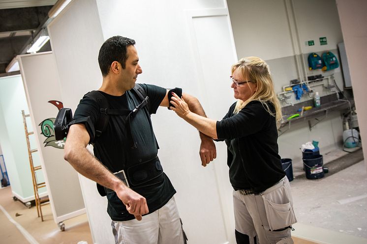 Anita Jensen hjælper Hamid med at få exoskelettet på.