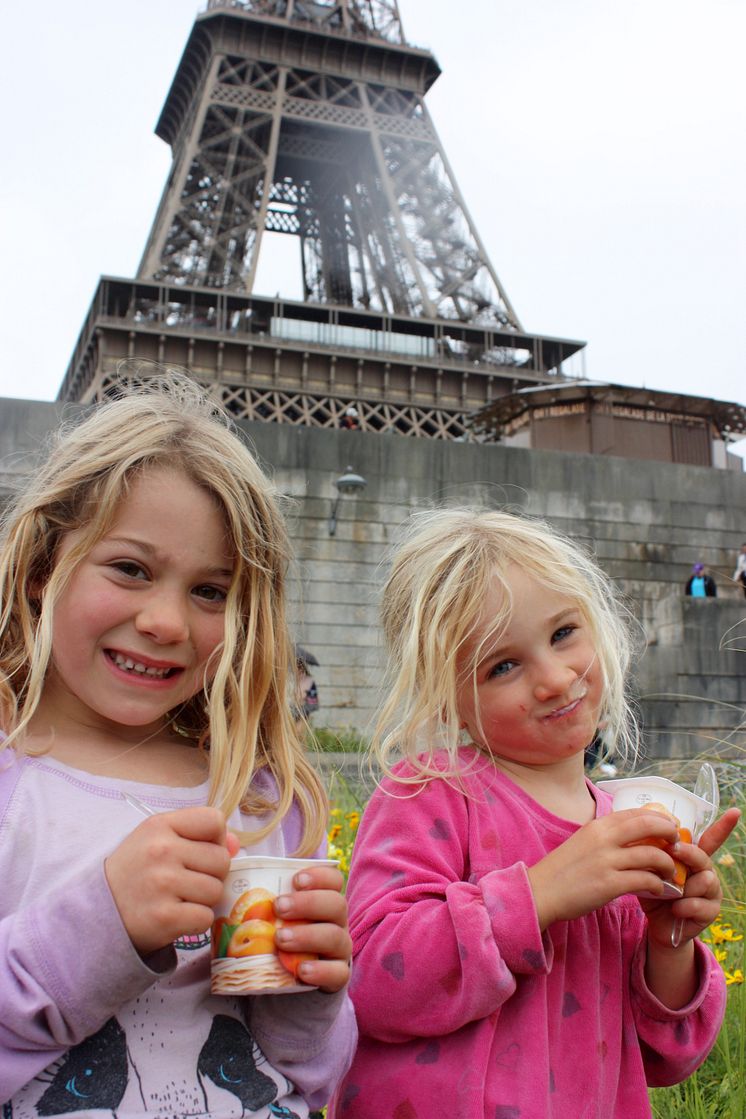 Søskenbarna Annabel og Louise nyter en Yoplait yoghurt med aprikose foran Eiffeltårnet.
