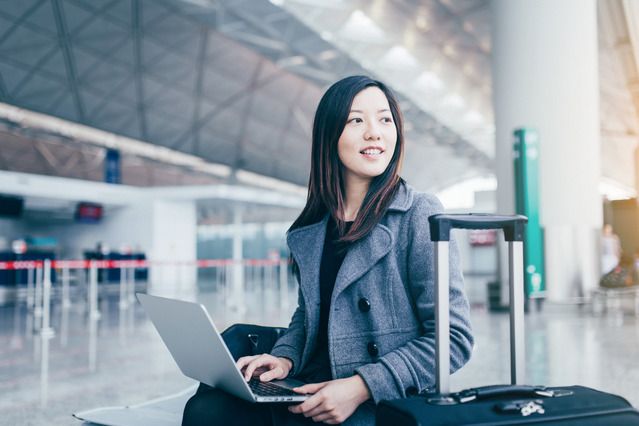 Woman using laptop and looking away at airport-2