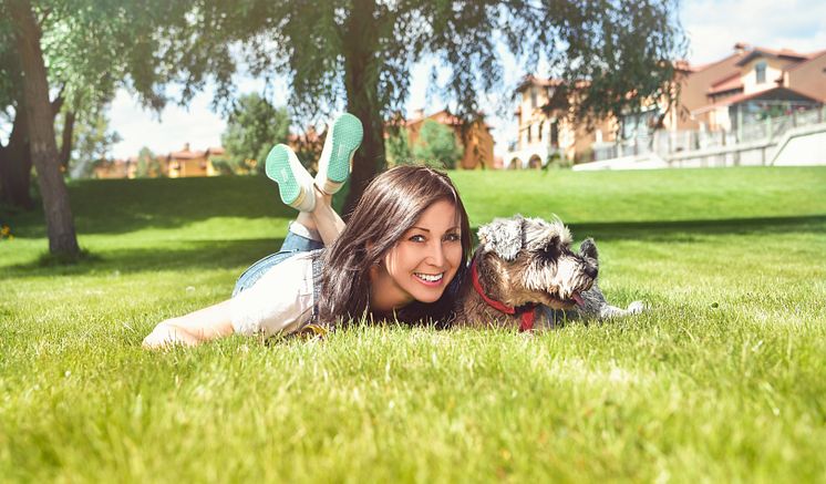 Frau mit Hund auf einer Wiese liegend