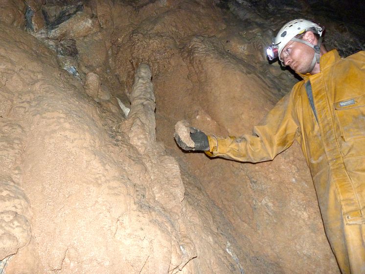 Prof Sebastian Breitenbach inside the cave with a stalagmite